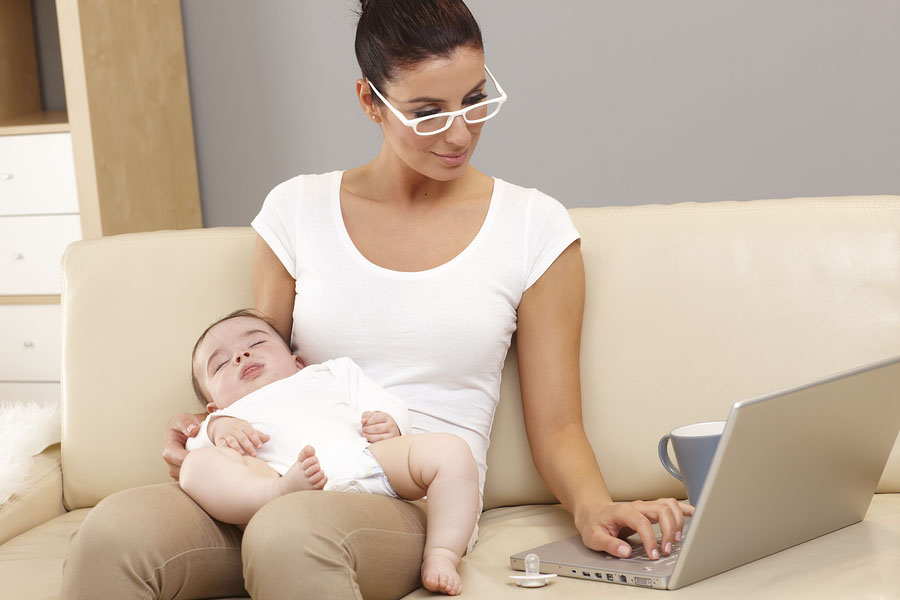 Vrouw bestelt online boodschappen achter laptop met baby op schoot