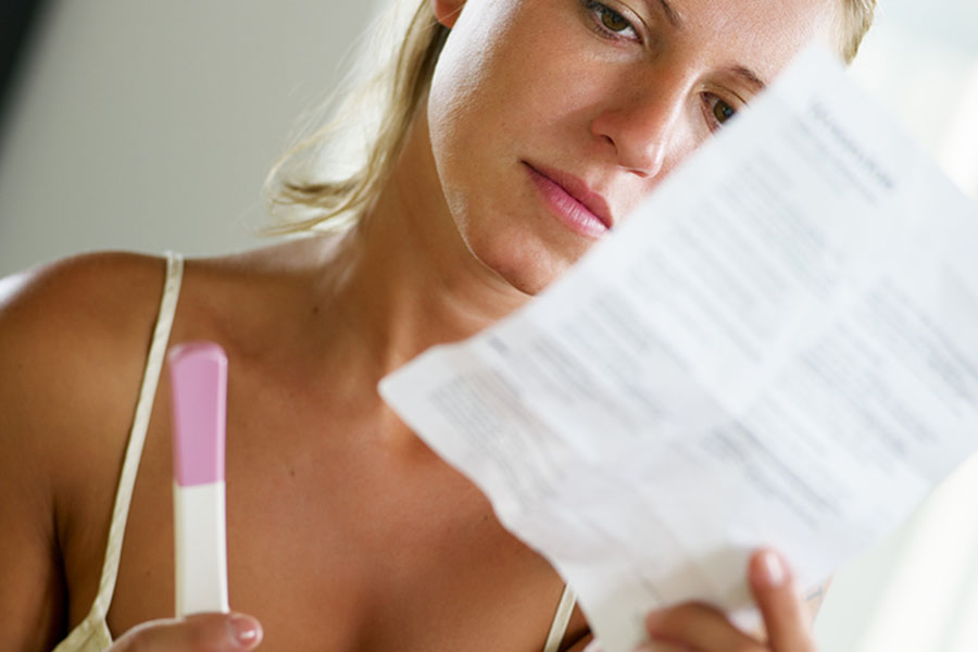Vrouw leest de gebruiksaanwijzingen van een zwangerschapstest