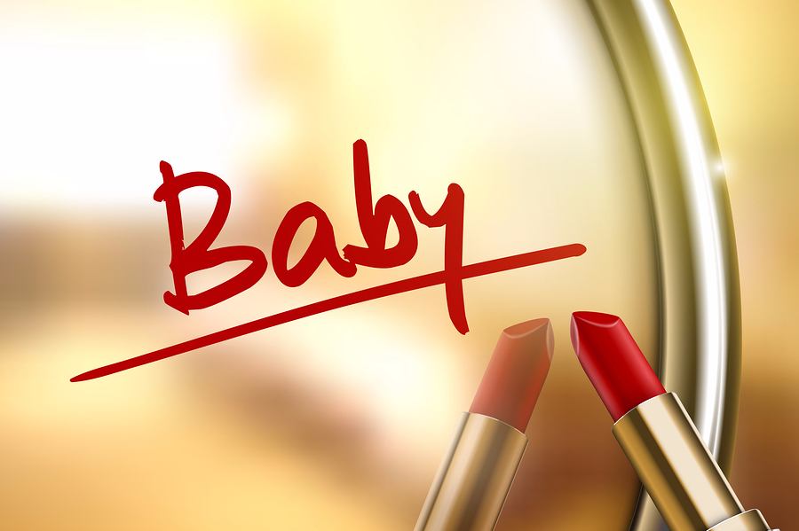Het woord baby met lippenstift geschreven op spiegel