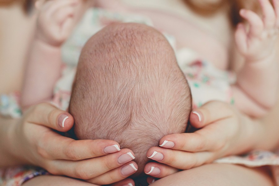 Moeder houdt hoofdje van baby vast