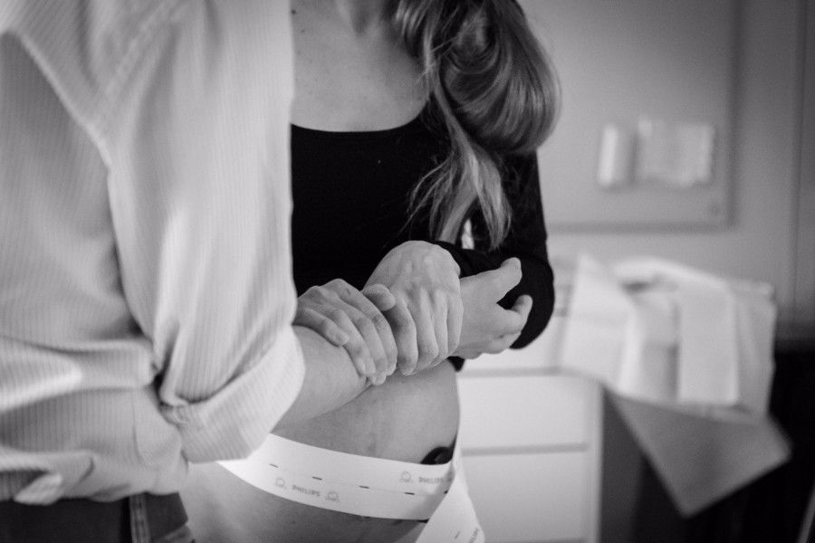 zwangere_vrouw_houdt_man_vast_bij_arm_tijdens_de_bevalling