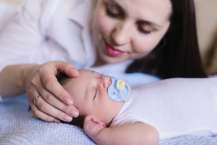 Moeder kijkt liefdevol naar slapend baby'tje met zeldzame ziekte