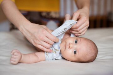 Moeder trekt baby een t-shirt aan bij hoge temperatuur