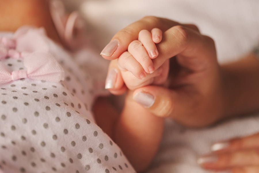 Baby houdt hand moeder vast