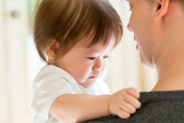 peuter met hechtingsstoornis zit erdrietig op arm van vader