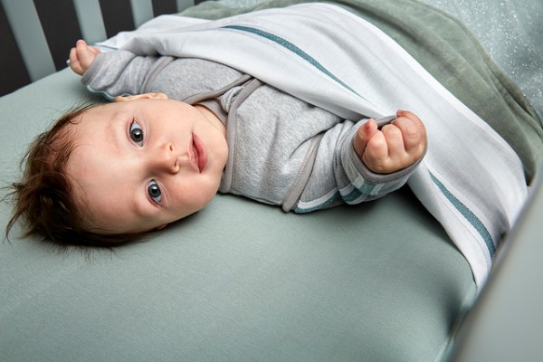 Baby ligt in een wieg onder een laken