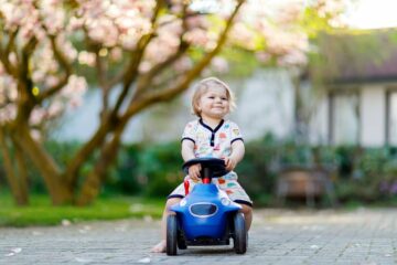 Meisje op blauwe loopauto