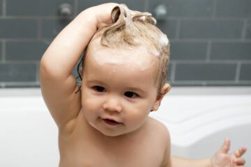 Peuter zit vrolijk in bad bij het haar wassen