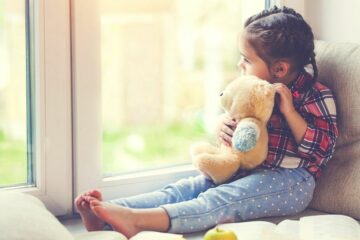 Peutermeisje kijkt verdrietig naar buiten na het scheiden van haar ouders