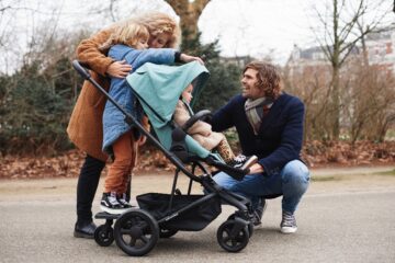 Jong gezin is met twee kinderen op pad met de kinderwagen accessoire