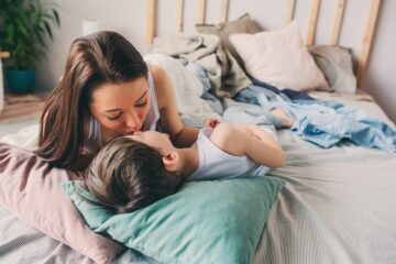 Moeder troost zoontje op bed terwijl hij last heeft van groeipijn