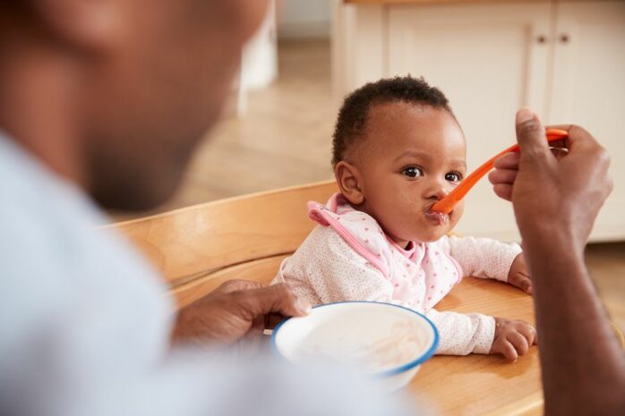 Vader geeft baby eten volgens voedingsschema baby 9 maanden