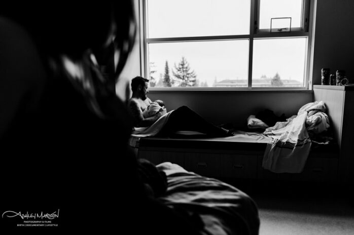 Vader houdt pasgeboren baby vast terwijl moeder toekijkt