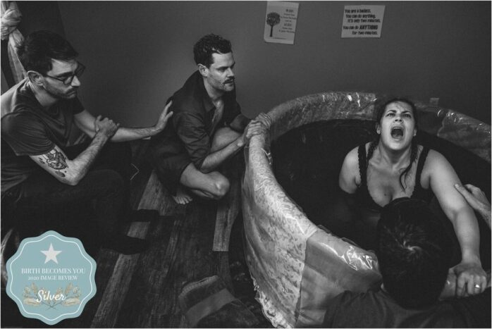 Draagmoeder vangt weeën op in bad terwijl de aankomende vaders haar ondersteunen