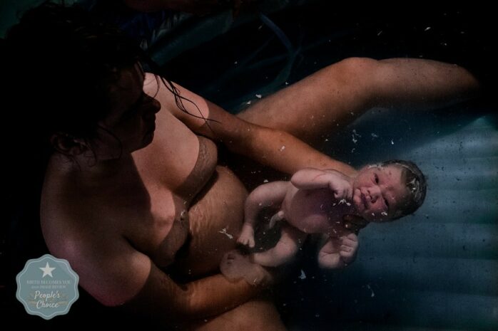 Baby in bad bij moeder na bevalling met vlokken in het water