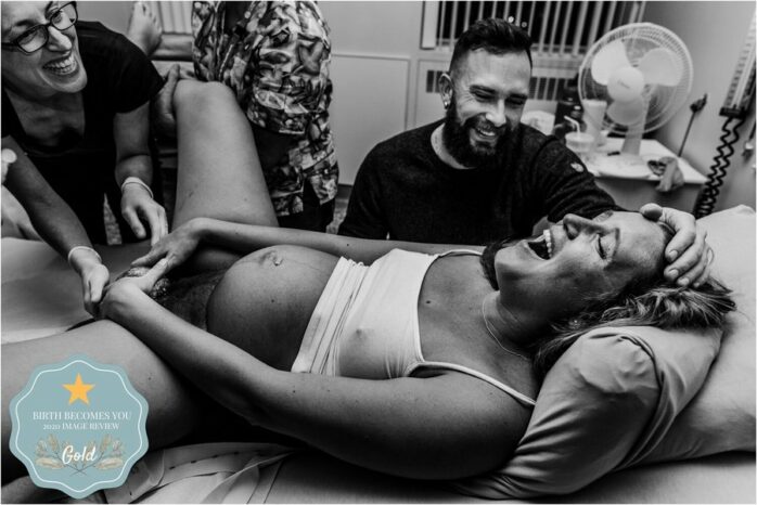 Vrouw en partner lachen terwijl de baby geboren wordt