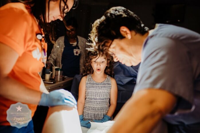 Grote zus kijkt mee met de bevlling