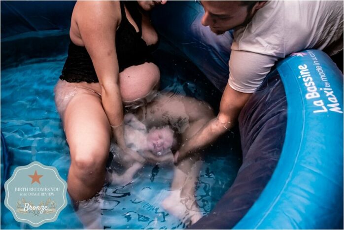 Kersverse vader vangt de baby op bij een badbevalling