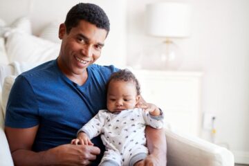 Vader geniet van zijn geboorteverlof met baby op schoot