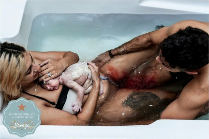 Pasgeboren baby onder de vernix ligt bij zijn moeder op de borst in bad