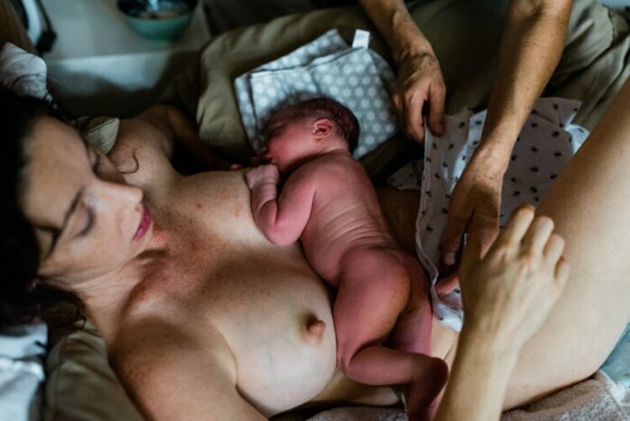 Pasgeboren baby ligt naakt aan de borst bij zijn moeder