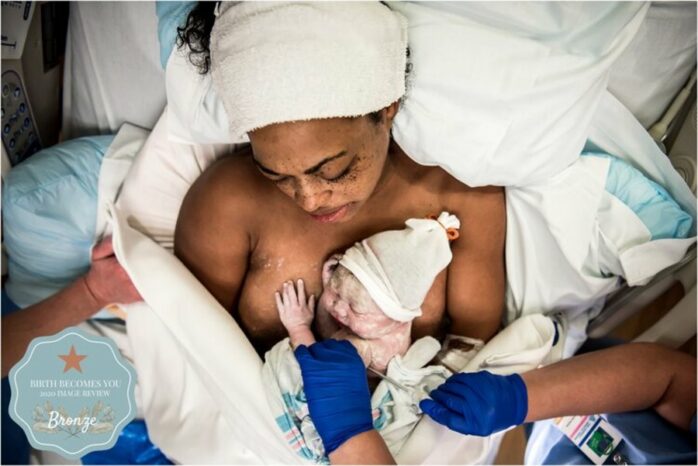 Pasgeboren baby ligt vredig bij zijn moeder op de borst