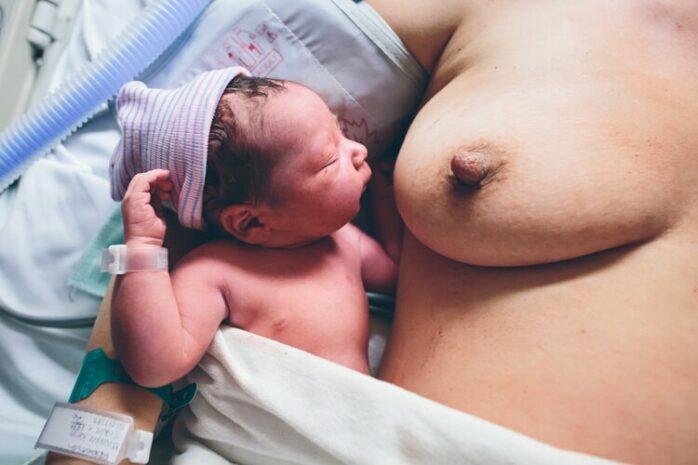 Pasgeboren baby ligt naast de borst van zijn moeder