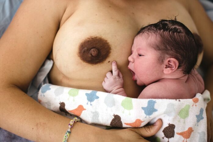 Pasgebroen baby hapt naar de tepel van zijn moeder