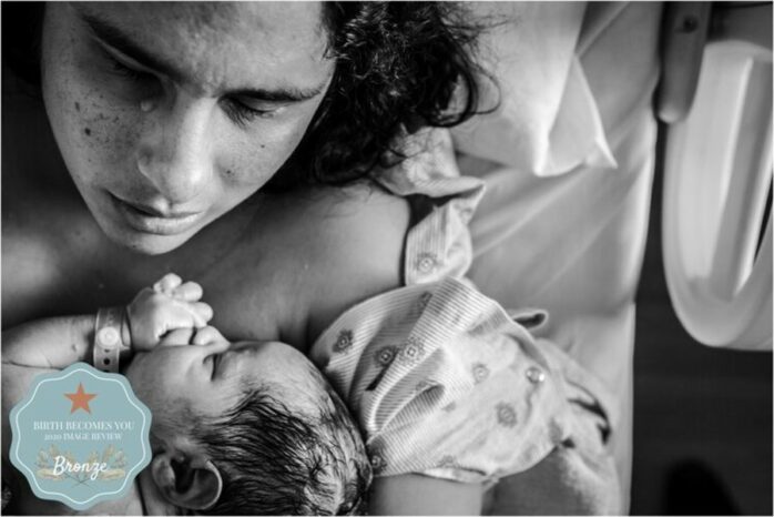 Er loopt een traan over de wang van moeder die pasgeboren baby in haar armen heeft