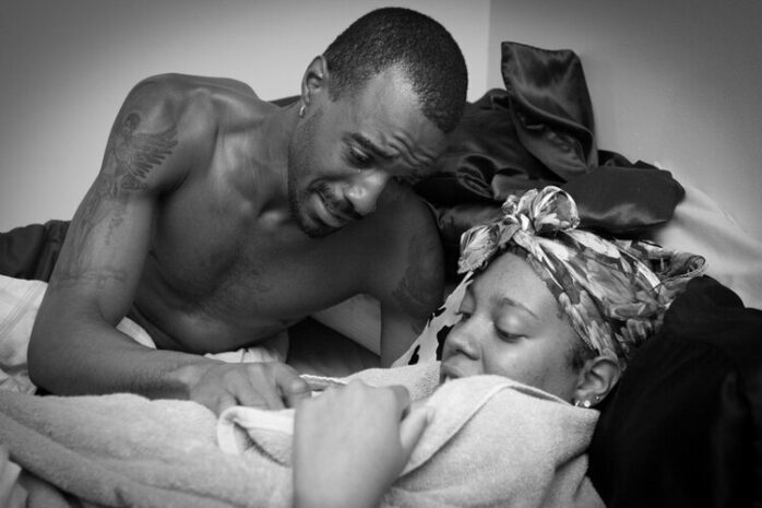 Vader bekijkt geëmotioneerd naar zijn pasgeboren baby, er loopt een traan over zijn wang