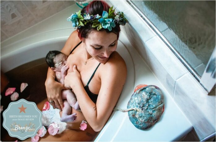 Vrouw heeft baby aan de borst in bad en bekijkt haar placenta