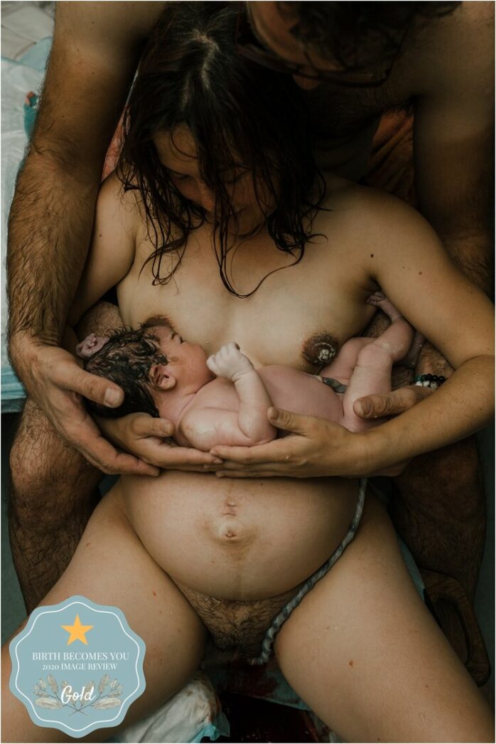 Moeder en vader houden samen hun pasgeboren baby en elkaar vast