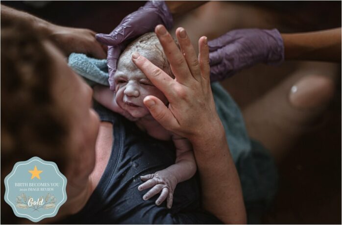 Pasgeboren baby onder de vernix ligt bij moeder op de borst