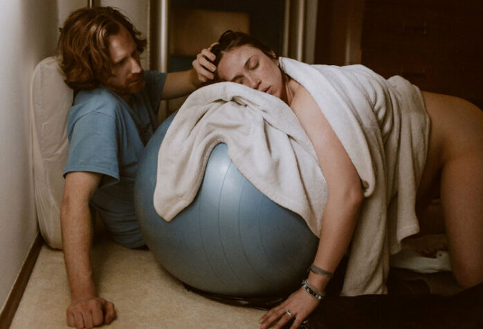 Vrouw ligt op fitnessball en vangt zo weeën op