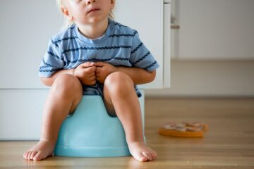 Kindje met obstipatie zit op het potje en probeert te poepen, maar het gaat moeizaam
