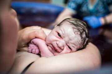 Pasgeboren baby heeft nog een verfrommeld uiterlijk en is bedekt met een laagje vernix