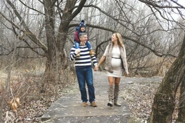 Gezin met vader, zwangere moeder en zoontje lopen door het bos in de herfst