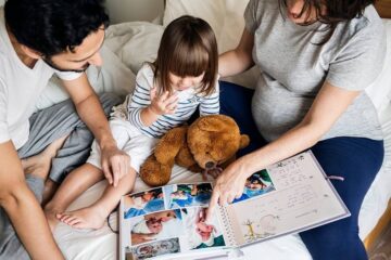 Vader en zwangere moeder bereiden hun kind voor op een broertje of zusje door foto's te kijken van haar babytijd