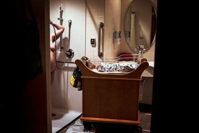 Pasbevallen vrouw onder de douche terwijl baby dichtbij is
