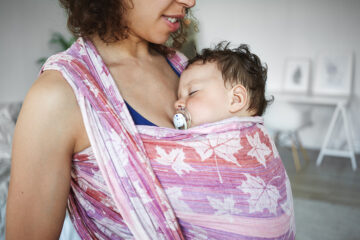 Moeder draagt baby in draagdoek