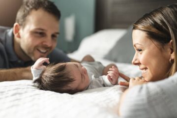 Ouders kijken naar hun pasgeboren baby die op bed ligt