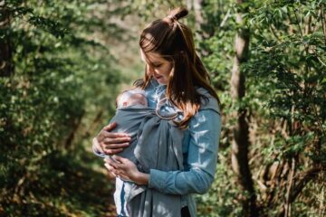 Moeder draagt baby in ringsling