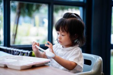 Peuter zit aan tafel in een kinderstoel