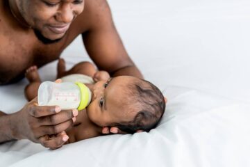 Vader geeft baby fles die is opgewarmd in flessenwarmer