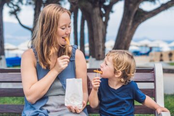 Moeder geniet tijdens haar zwangerschap van fastfood met haar zoontje in het park