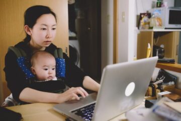 Moeder zit met baby voor de laptop