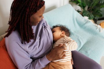 Moeder voedt baby en denkt na over de zorgverzekering van haar kind.