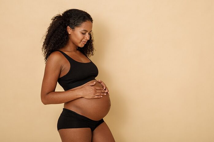 Zwangere vrouw heeft handen op haar zwangere buik