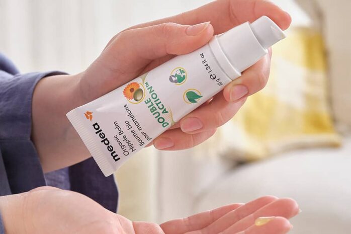 Vrouw smeert biologische tepelbalsem van Medela op vinger