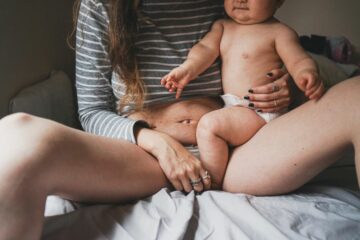 Een postpartum vrouw met een verzakking van de baarmoeder die haar baby op schoot heeft.